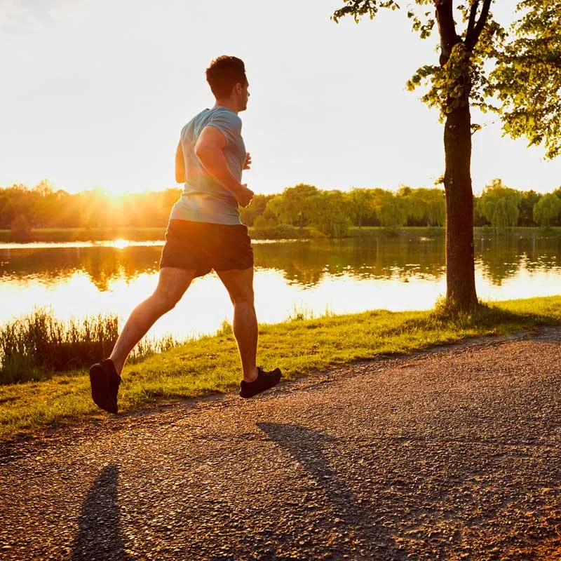 a man jogs along a park path at sunset
