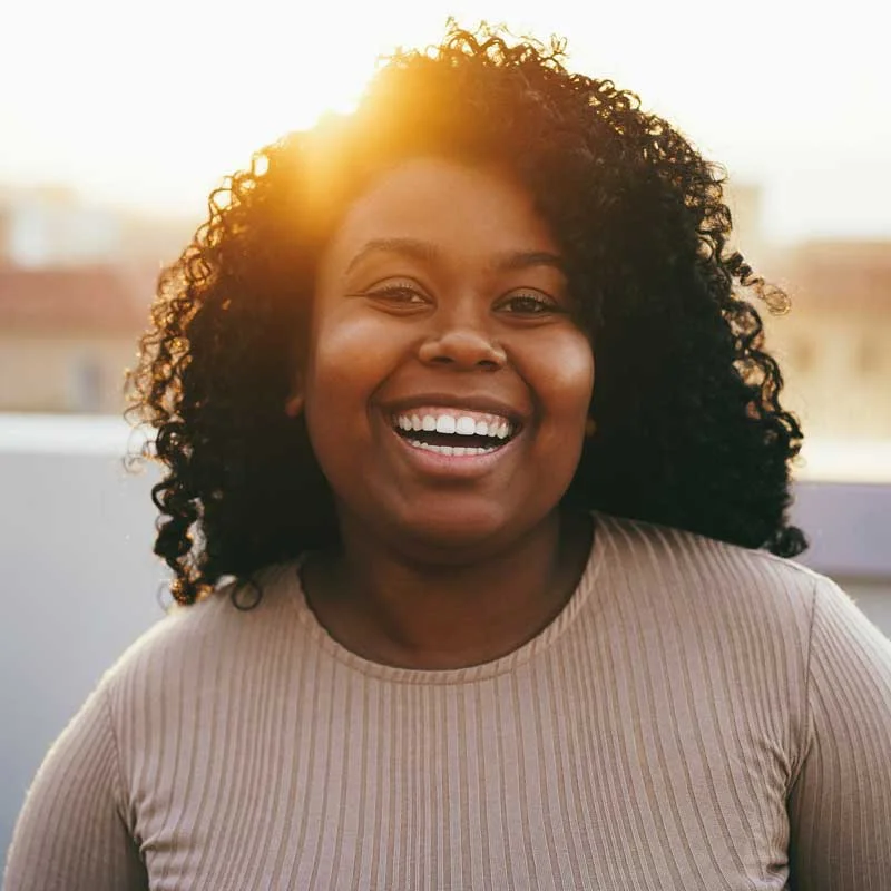 a young woman with curly hair smiles at the camera