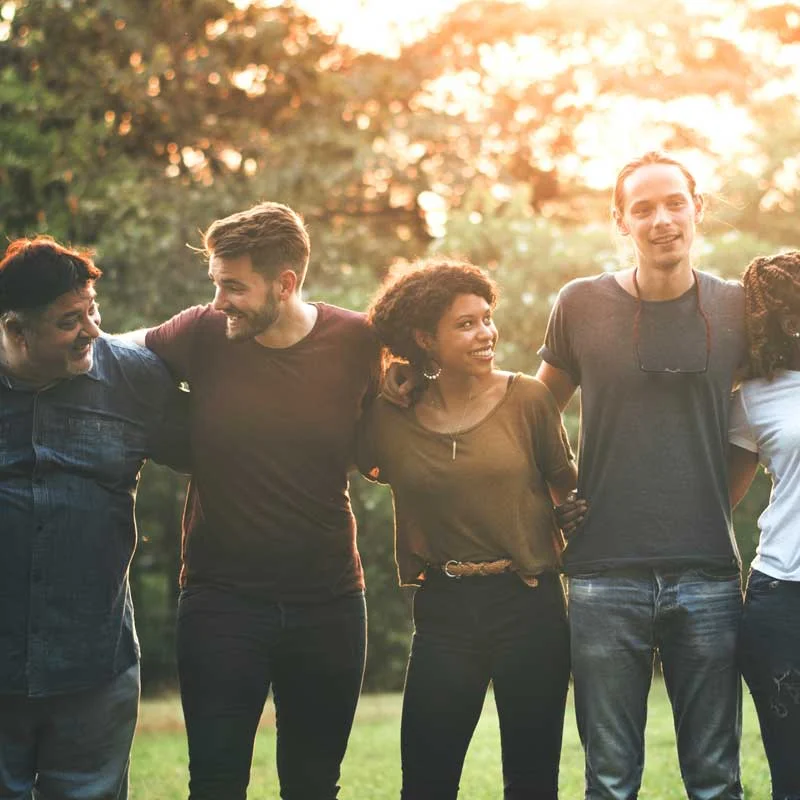 a diverse group of friends poses for a picture at the park