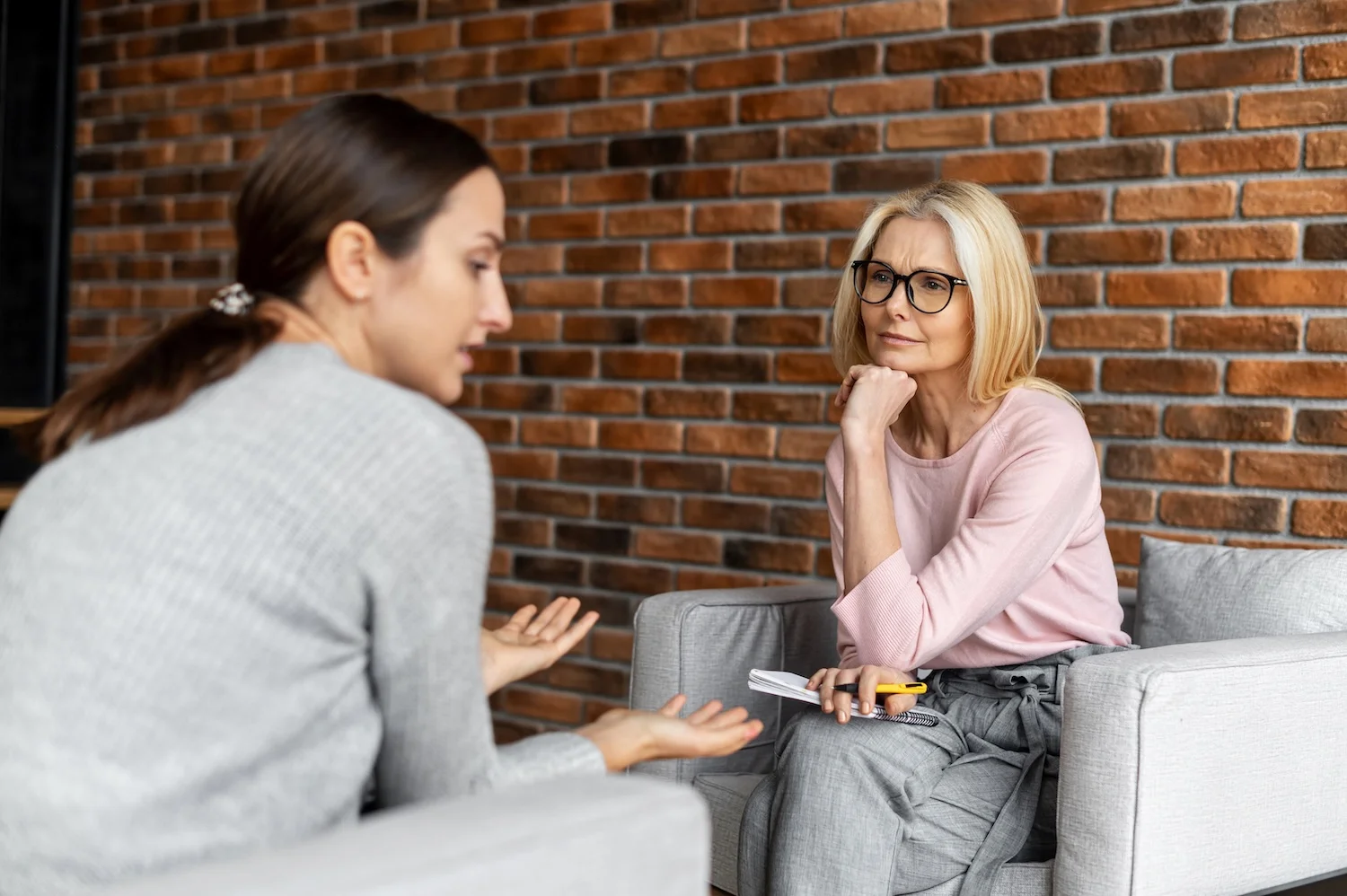 Therapist listening attentively as a woman speaks during a counseling session.